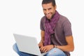 Smiling man sitting on floor using laptop looking at camera Royalty Free Stock Photo