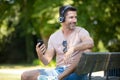 smiling man sitting on park bench with headphones Royalty Free Stock Photo