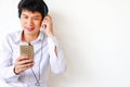 Smiling man sitting relaxed on the floor listening to music on earphones, holding phone in his hand, lifestyle concept Royalty Free Stock Photo