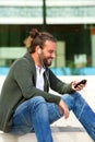 Smiling man sitting on steps listening to music with smart phone Royalty Free Stock Photo