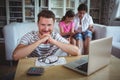 Smiling man sitting at table with bills and laptop Royalty Free Stock Photo