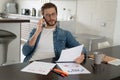 Smiling man, he is sitting at a table, talking on the phone with his laptop, notebook and glasses in front of him Royalty Free Stock Photo