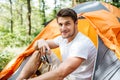 Smiling man sitting and using old photo camera in forest Royalty Free Stock Photo