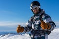 Smiling man in skiing or snowboarding winter equipment shows thumbs up. Warm jacket, brown gloves, ski goggles, helmet Royalty Free Stock Photo