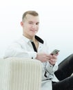 Smiling man with smartphone sitting on sofa in his living room Royalty Free Stock Photo