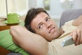 Smiling man on sofa using remote control