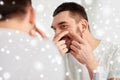 Smiling man squeezing pimple at bathroom mirror Royalty Free Stock Photo