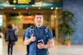 Smiling man standing at modern airport departure terminal holding passport and boarding pass Royalty Free Stock Photo