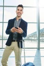 Smiling man standing in station with suitcase and phone Royalty Free Stock Photo