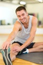 Smiling man stretching on mat in the gym