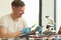 Smiling man studies broken motherboard in repair workshop Royalty Free Stock Photo