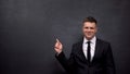 Smiling man in suit pointing finger into blackboard, business workshop, success