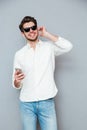 Smiling man in sunglasses listening to music from mobile phone Royalty Free Stock Photo