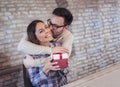 Smiling man surprises his girlfriend with present at home