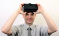 A smiling man taking off or putting on Oculus Rift VR virtual reality headset, positively impressed