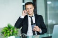 Smiling man talking on mobile phone while using laptop computer at desk Royalty Free Stock Photo