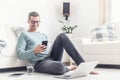 Smiling man texts on his mobile phone during his home office hours at home, sitting on a living room floor Royalty Free Stock Photo