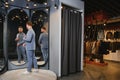 Smiling man trying on suit at mirror in menswear shop