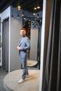 Smiling man trying on suit at mirror in menswear shop