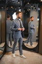 Smiling man trying on suit at mirror in menswear shop