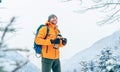 Smiling Man under snowfall dressed bright orange softshell jacket with a hot drink thermos flask while he trekking winter Royalty Free Stock Photo