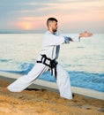 Man in uniform doing taekwondo exercises at sunset sea shore Royalty Free Stock Photo