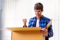 Smiling man unpacking awaited parcel, looking inside, sitting with a curtain in the background, satisfied happy customer opening