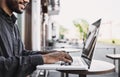 Smiling man using laptop computer in a city. Young handsome student having coffee break.