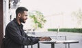 Smiling man using laptop computer in a city. Young handsome student having coffee break. Royalty Free Stock Photo