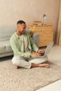 Smiling Man Using Laptop At Home. Young Guy Holding Computer, Sitting At Floor Royalty Free Stock Photo