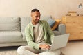 Smiling Man Using Laptop At Home. Young Guy Holding Computer, Sitting At Floor Royalty Free Stock Photo