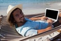 Smiling man using laptop while relaxing on hammock in beach Royalty Free Stock Photo