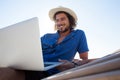 Smiling man using laptop while relaxing on hammock at beach Royalty Free Stock Photo