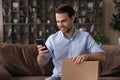 Smiling man using smartphone, holding cardboard box, unpacking parcel