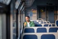 Smiling man using smartphone, scrolling social media and messaging, seated by the window in train Royalty Free Stock Photo