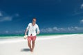 Smiling  man walks on the beach with hat in hand Royalty Free Stock Photo