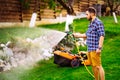 Close up of smiling man watering backyard lawn using hose. Irrigation systems Royalty Free Stock Photo