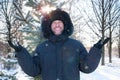 Smiling man wearing fur hooded parka coat in the winter park Royalty Free Stock Photo