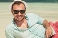 Smiling man wearing sunglasses and laying down the beach Royalty Free Stock Photo