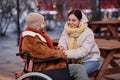 Smiling man in wheelchair holding hands with girlfriend in winter date