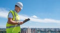 Smiling man in white helmet at construction site writes notes on clipboard Royalty Free Stock Photo