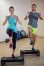 Smiling man and woman doing step aerobic exercise on stepper Royalty Free Stock Photo