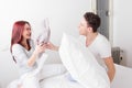 Smiling man and woman fighting with pillows together in bed Royalty Free Stock Photo