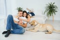 Smiling man and woman sitting on floor at home with their pet dog. Portrait of happy dog loving family with their pet dog Royalty Free Stock Photo