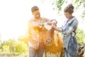 Smiling man and woman standing with cow at farm and yellow lens flare in background