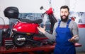 smiling man worker displaying his workplace in motorcycle workshop Royalty Free Stock Photo