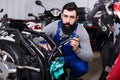 Smiling man worker fixing failed motorcycle Royalty Free Stock Photo