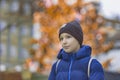 A smiling man of 12 years in a blue jacket and a cap with a backpack standing on the street and behind him is a super bokeh Royalty Free Stock Photo