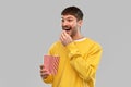 Smiling man in yellow sweatshirt eating popcorn