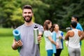 Smiling man with yoga mat over group of people Royalty Free Stock Photo